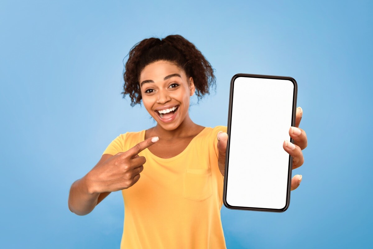 Femme sourit en montrant son smartphone, contente des 50 Go gratuits en plus avec Coriolis